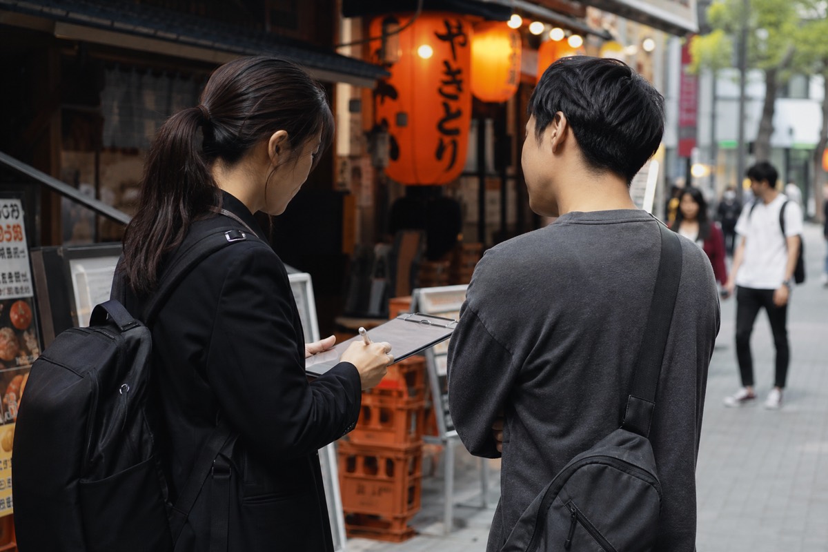 飲食店街で街頭ヒアリングを行うスタッフ